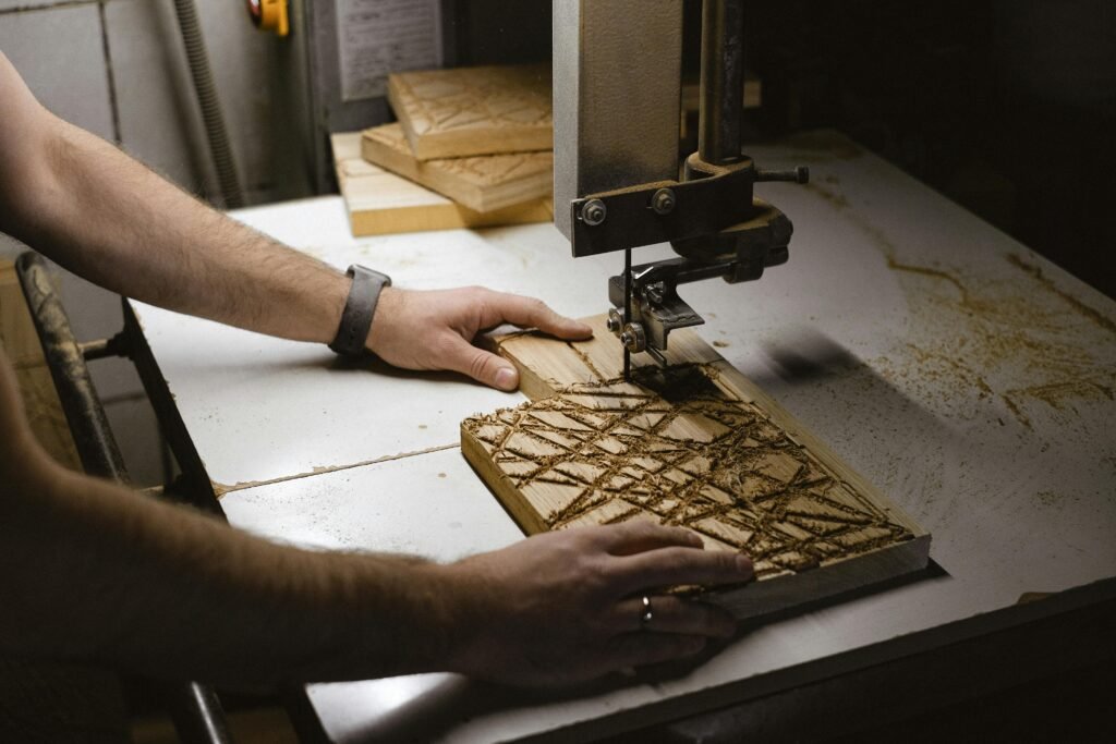 A craftsman uses a lathe to work on a carved wooden plank in a workshop.