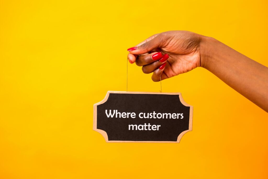 A close-up of a hand holding a sign stating Where customers matter against a bright yellow background.